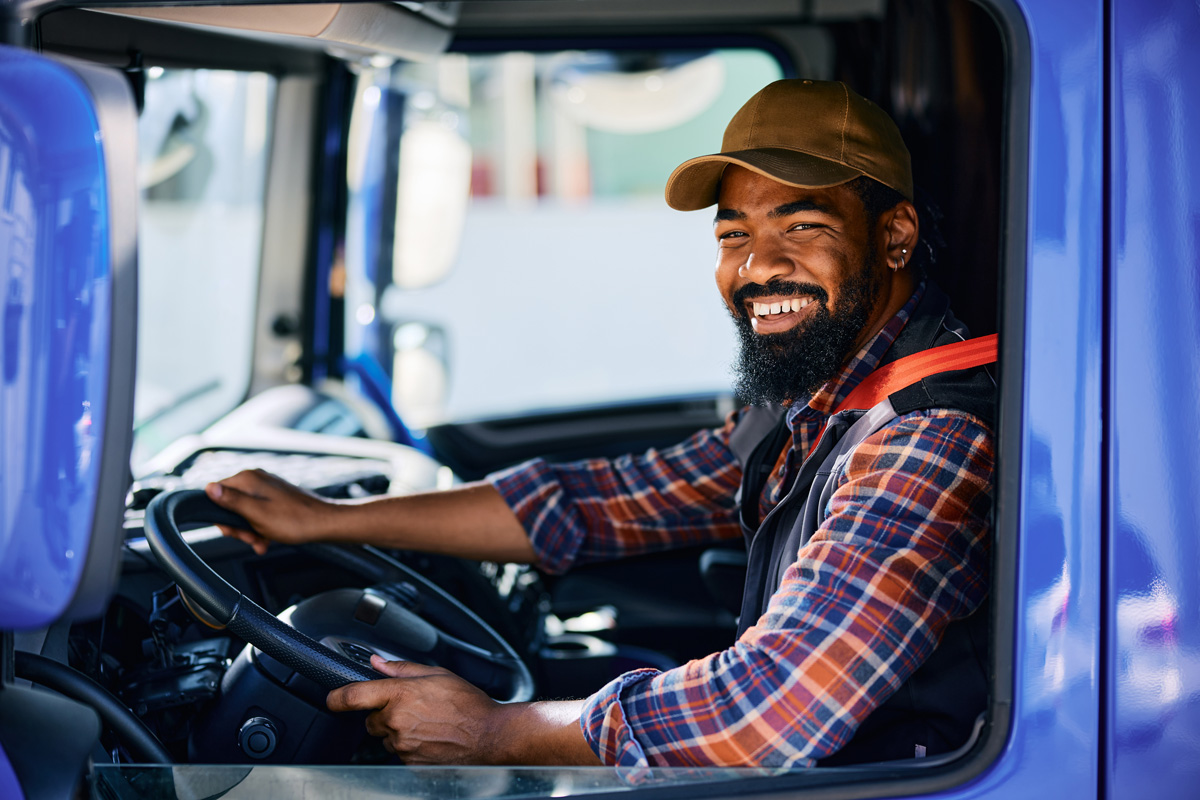 A man smiling in the driver’s seat of a commercial truck in El Paso.